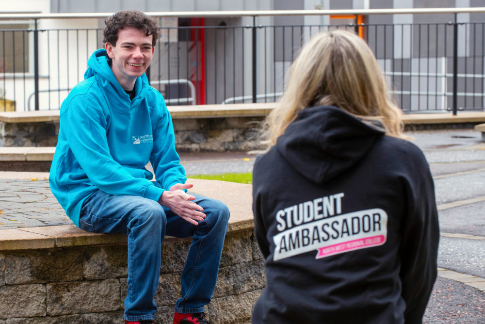 Male and female student ambassadors chat together outside the College